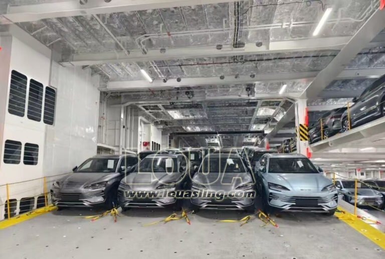Row of grey passenger cars secured by color-coded yellow 4-point wheel lashing straps to cloverleaf deck sockets.